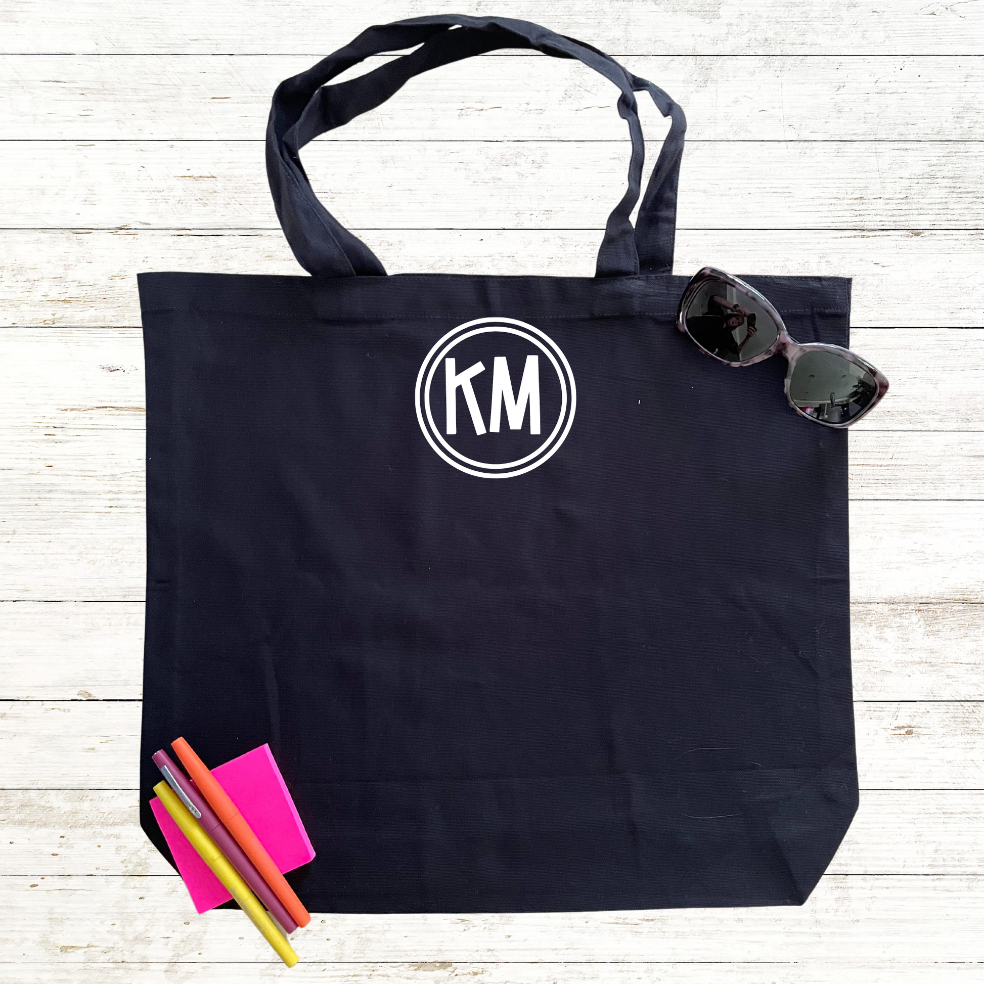 Black tote bag featuring personalized initials on the back, available for an additional charge. Customize your bag with your unique initials for a personal touch. Perfect for swim teams, individuals, or as a thoughtful gift. The addition of custom initials makes this tote even more special and one-of-a-kind.