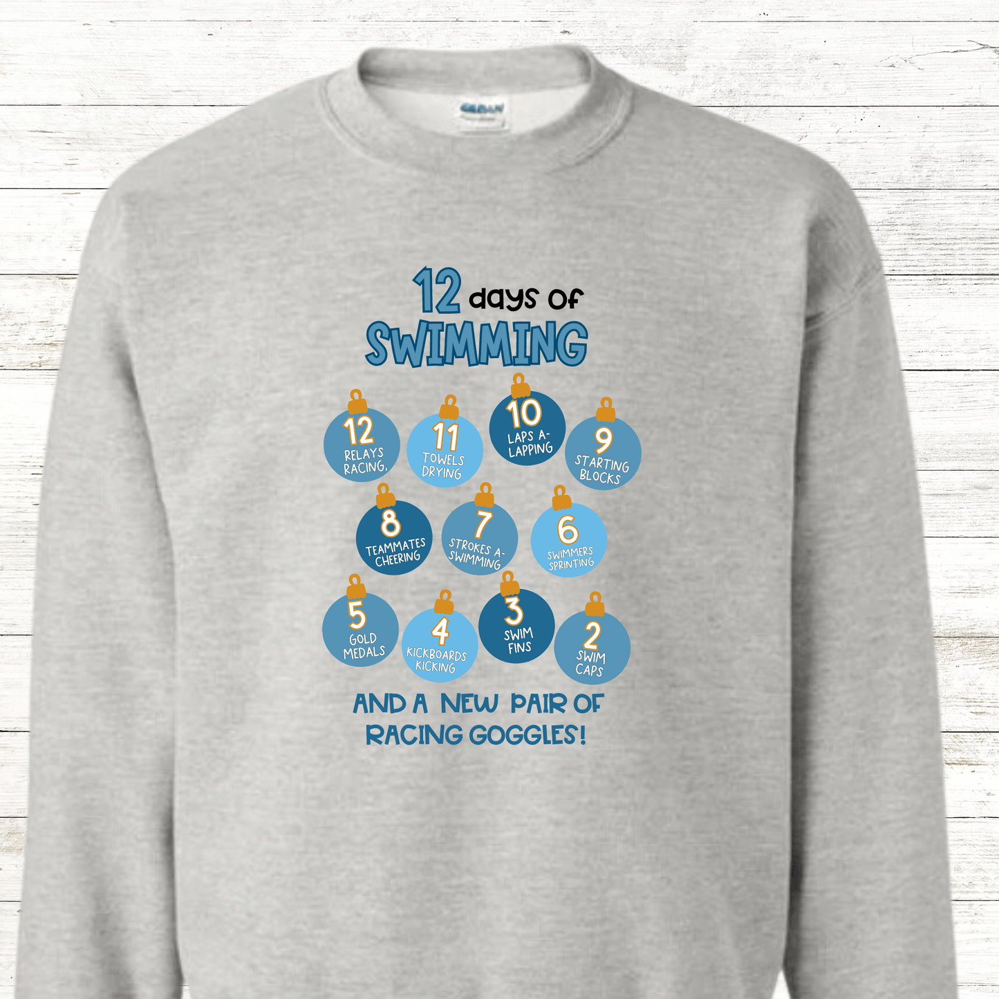 A festive "12 Days of Swimming - Christmas Edition" shirt featuring a fun holiday design with swimming-themed elements. Available in shirts and sweatshirts, perfect for celebrating the season with a splash.