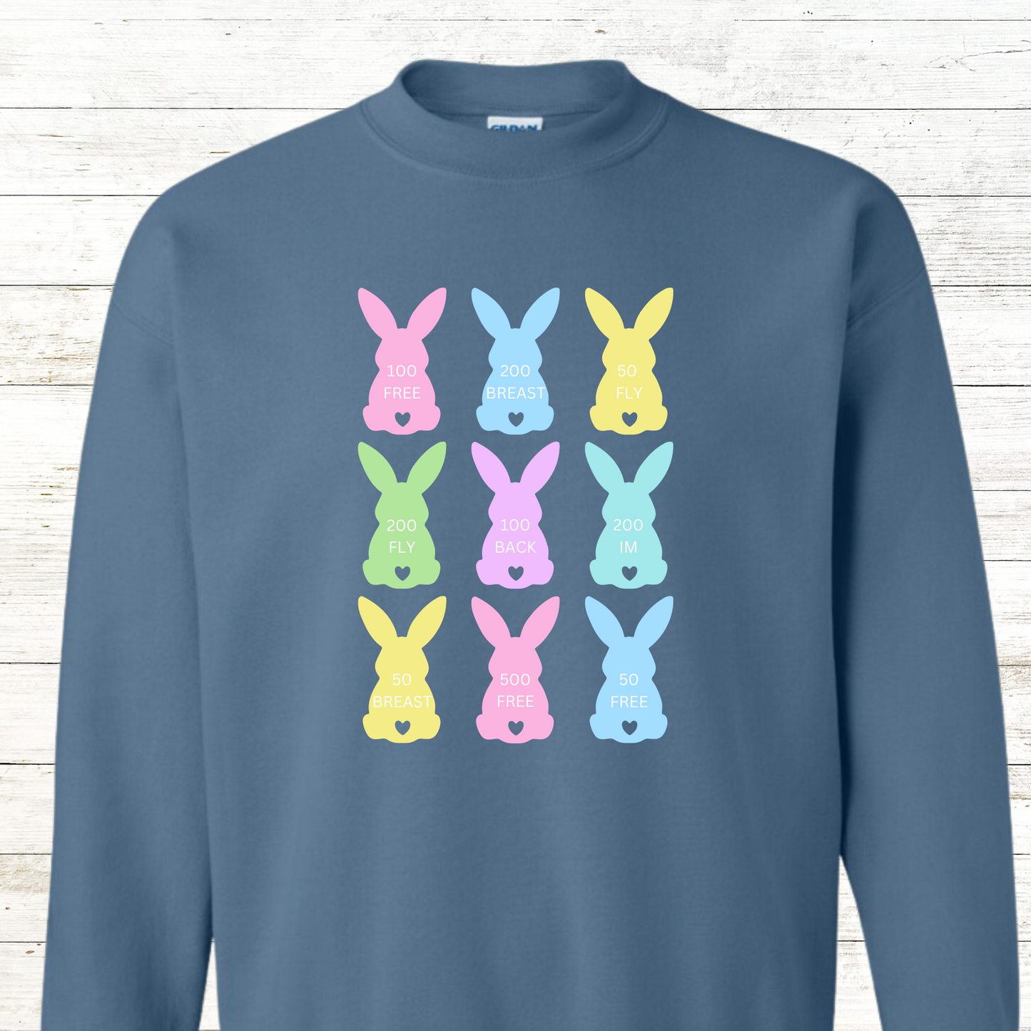 Swim-themed Easter design featuring pastel bunny peeps, each showcasing a different swim stroke—freestyle, backstroke, breaststroke, and butterfly. Available on a t-shirt or sweatshirt. Personalization available for a small fee—add a first name, last name, team name, or more! Events include 100 Fly, 100 Breast, and 50 Back.